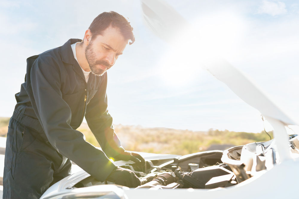 Mobile mechanic working under the hood of a car outdoors
